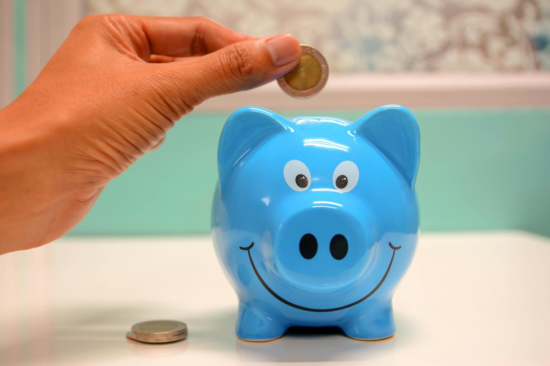 person putting coin in a piggy bank to save money by completing a noise survey